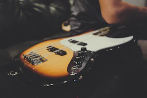 Close-up of a sunburst electric guitar resting on a vintage wooden floor.