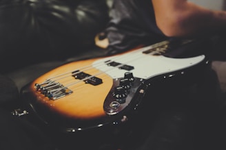 Close-up of a sunburst electric guitar resting on a wooden floor with soft natural light.
