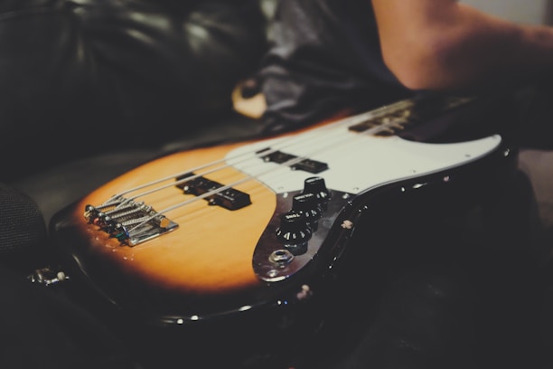Close-up of a sunburst electric guitar resting on a wooden floor with soft natural light.