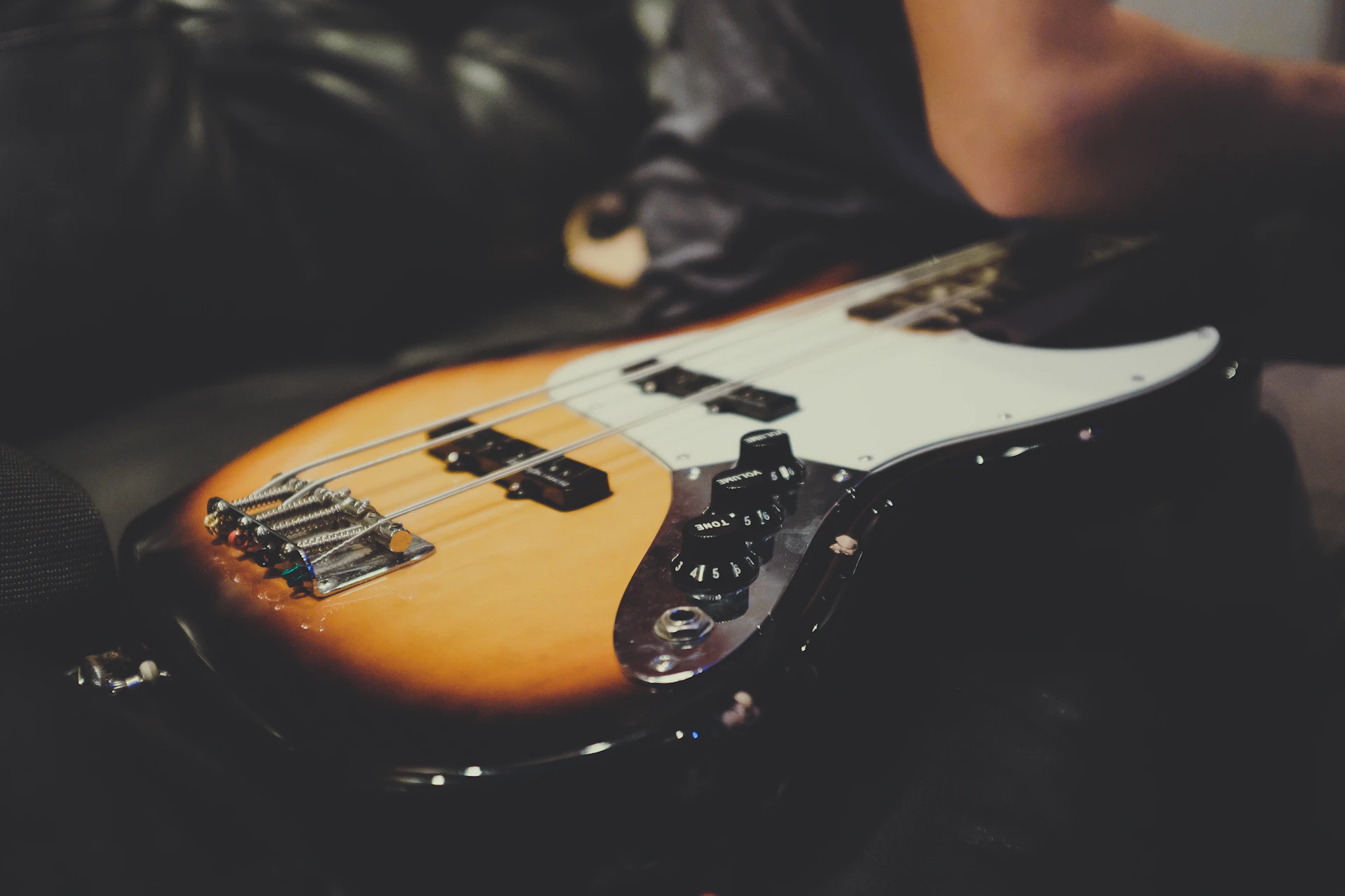 A close-up shot of a sunburst electric guitar with vintage wear, resting on a wooden floor.
