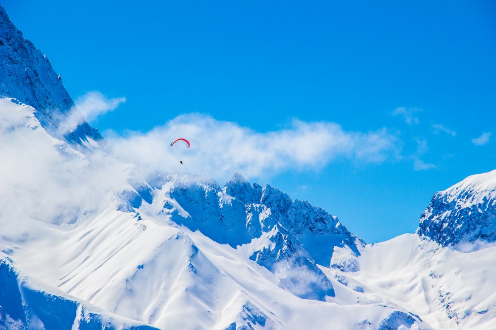 눈 덮인 산 위에 낙하산을 펼친 사람의 사진