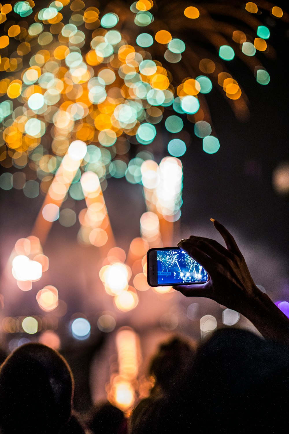 person holding smartphone capturing fireworks