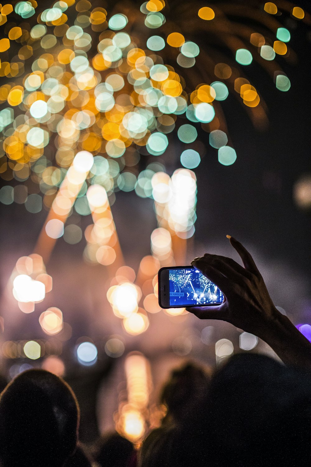 Persona che tiene lo smartphone che cattura i fuochi d'artificio