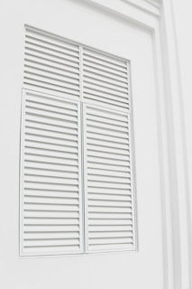 Close-up of elegant white plantation shutters perfectly fitted on a sunlit living room window.