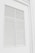 White louvered shutters set in a wall, with a clean, minimalist design. The shutters have horizontal slats that are evenly spaced.