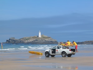 two men in white crew-cab pickup truck on shore