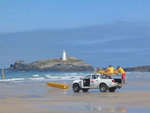 two men in white crew-cab pickup truck on shore