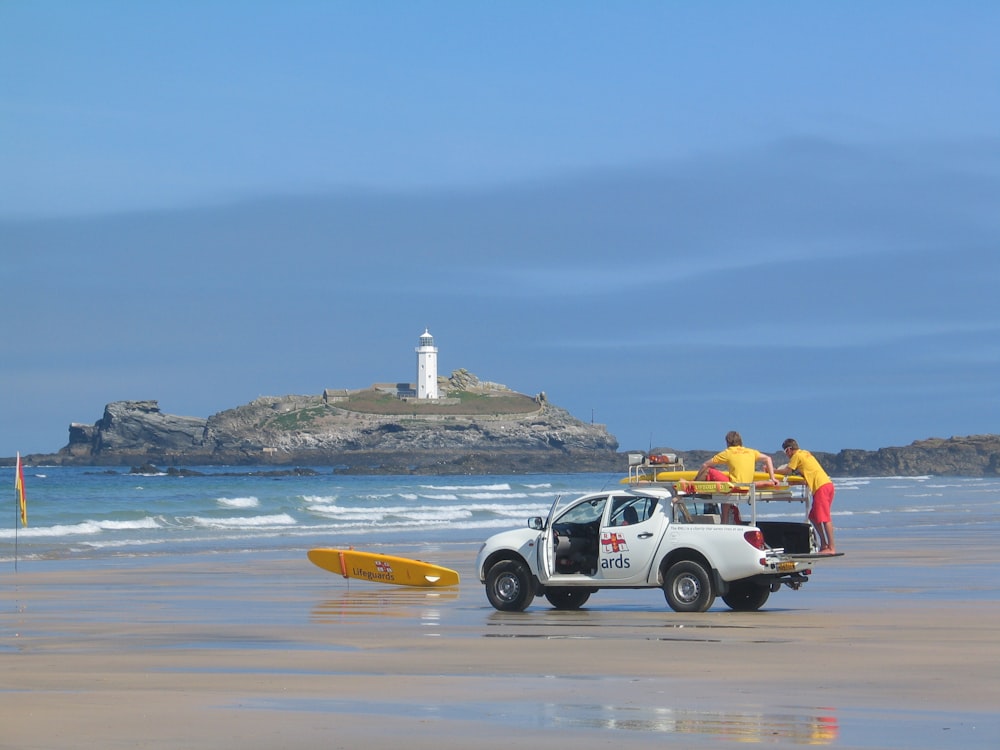 two men in white crew-cab pickup truck on shore