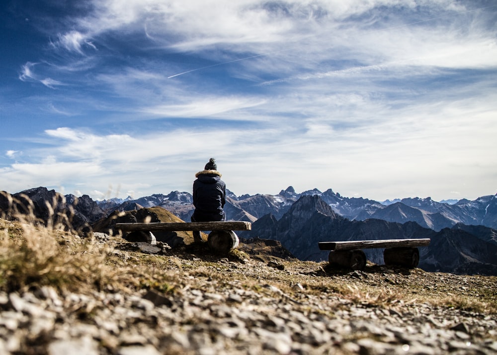 person sitting on bench near mountains