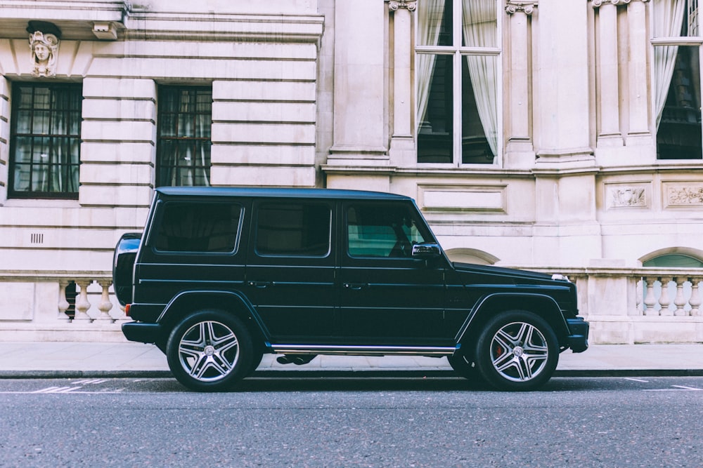 black Mercedes-Benz SUV parked beside white building