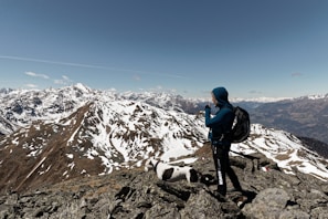 A traveler wearing a thick jacket standing on a mountain peak overlooking a valley