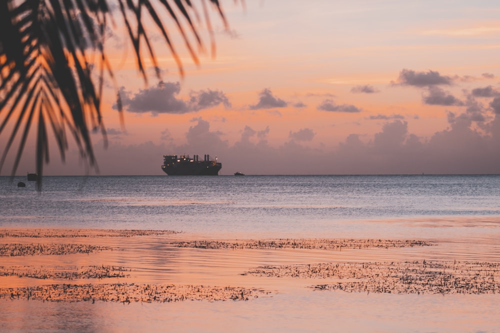 silhouette of ship on body of water during golden hour