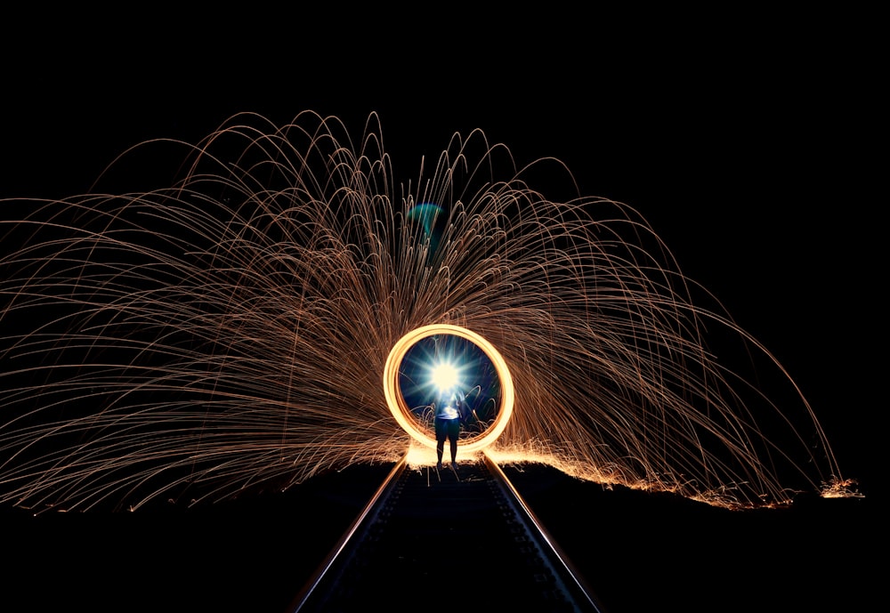 a person standing on a train track with fireworks in the background