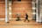 A musician stands under a decorated brick archway, playing a guitar. The blurred figure of a pedestrian is captured walking past the musician, adding a sense of motion to the scene. The background features an ornate brick and stone wall with inscriptions.