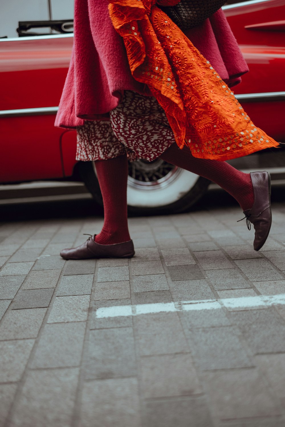 photo of person walking in front of red vehicle