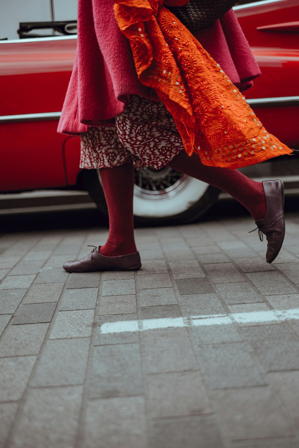 Foto de una persona caminando frente a un vehículo rojo