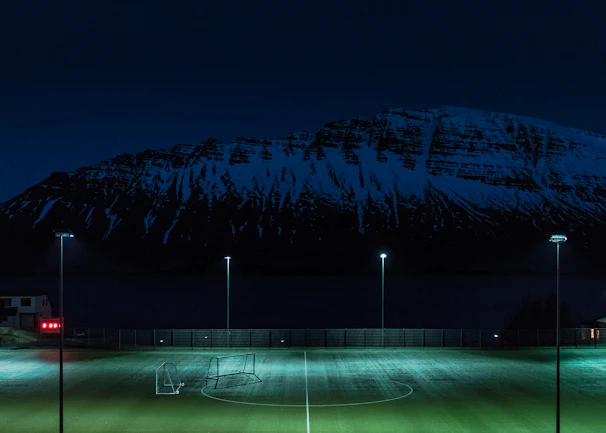 A vibrant graphic showing a mountain peak with football icons and team logos around it.