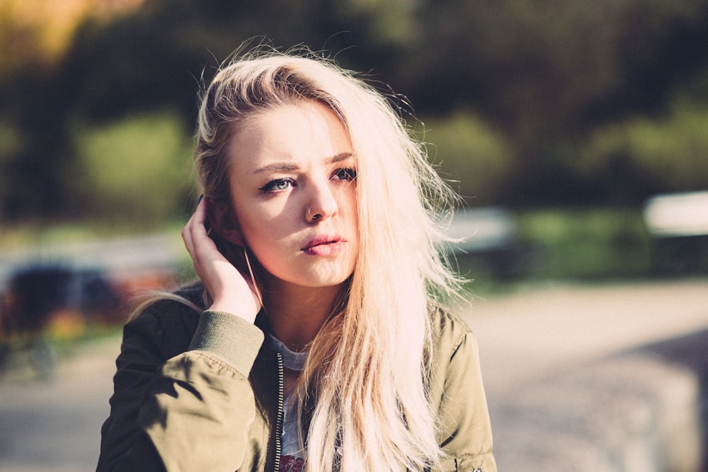 woman touching her hair near trees