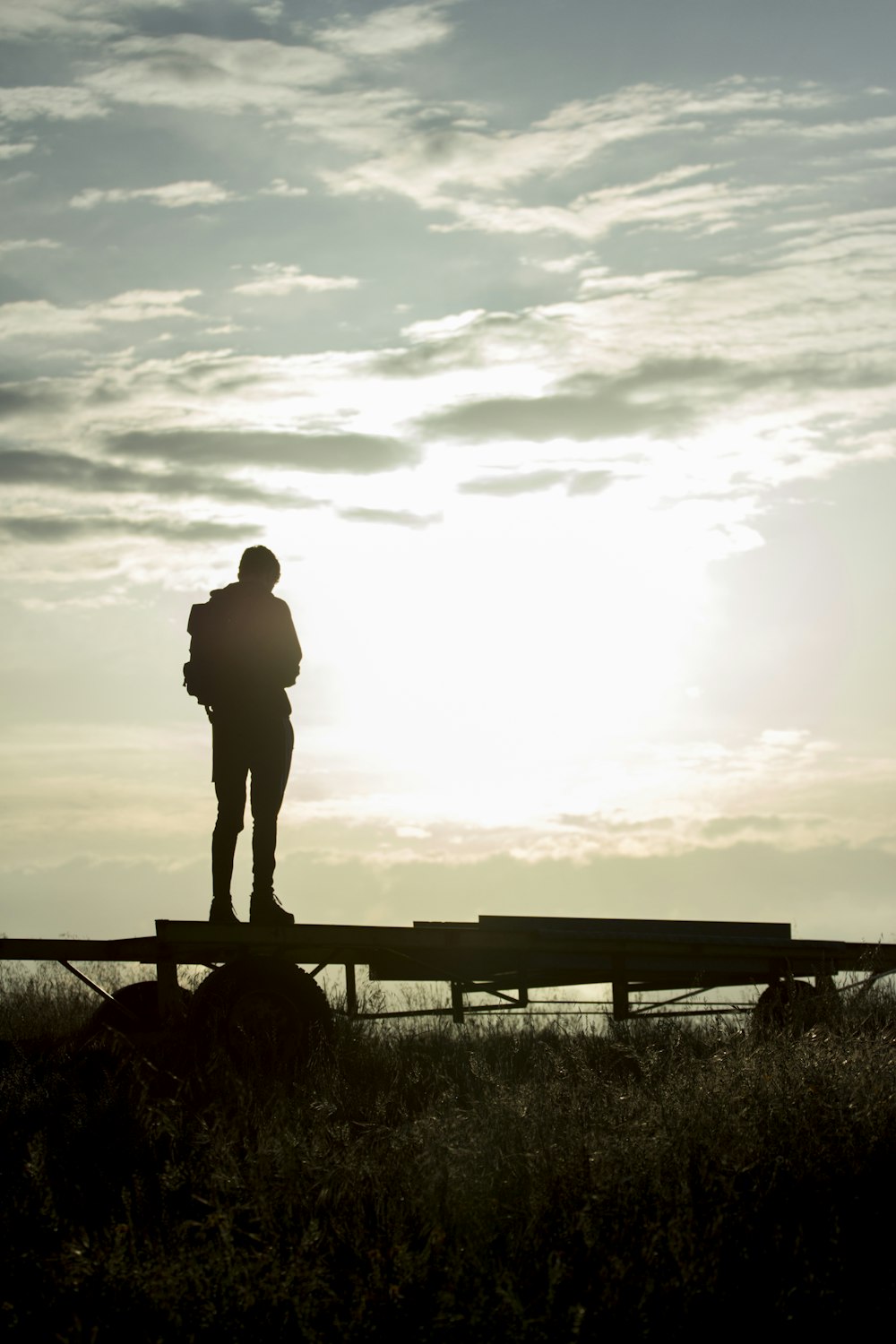 silhouette of man standing on wooden fence during sunset