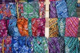 An array of colorful fabrics beautifully arranged for sale.