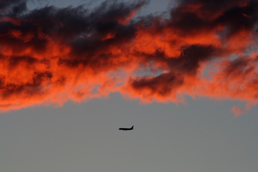 silhouette of plane on air under orange sky