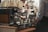 A barista using a commercial coffee machine in a busy café.