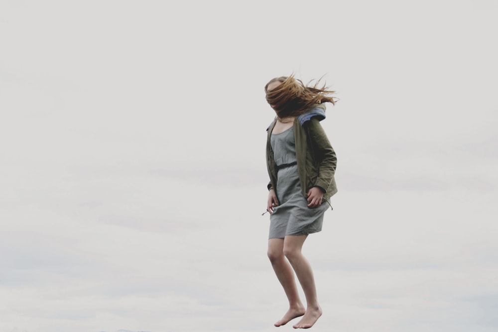 Fotografie einer Frau, die beim Springen mit ihren Haaren bedeckt ist