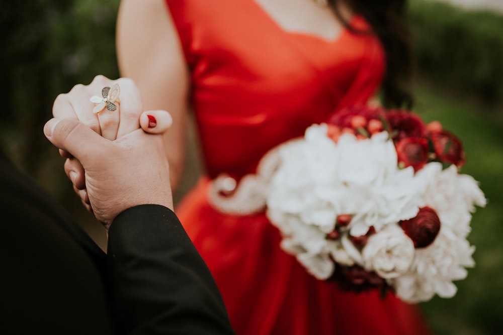 woman wearing red scoop-neck sleeveless dress holding white flower boquet