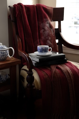 A steaming cup of antiwoke sleepy-time tea resting on a wooden bedside table, with soft evening light streaming through the window.