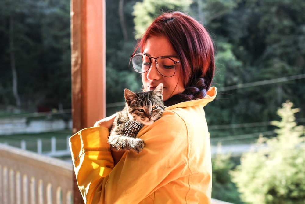 woman carrying cat while standing on porch