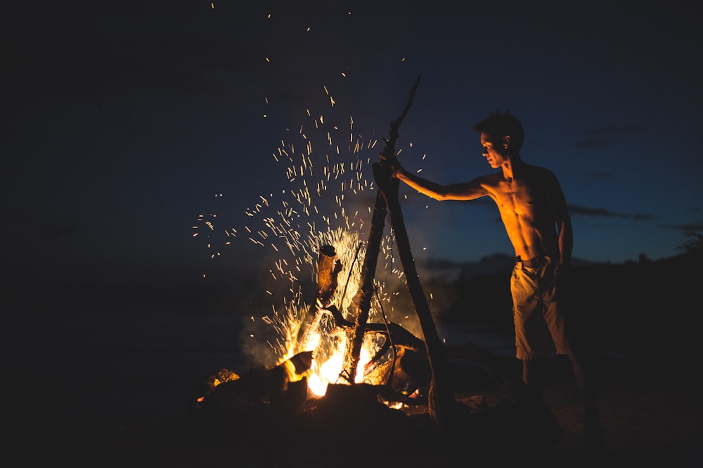 homme aux seins nus allumant un feu de joie