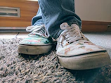 Close-up of feet in colorful sneakers tapping rhythmically on a wooden floor.