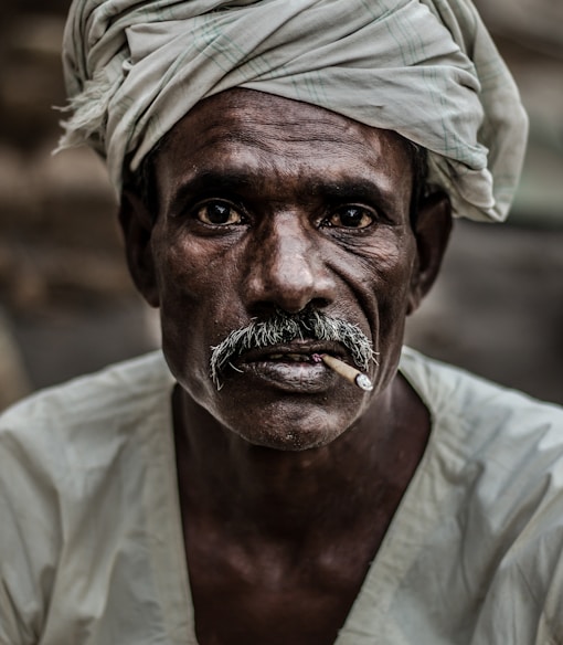 man wearing gray turban smoking cigarette in closeup photography