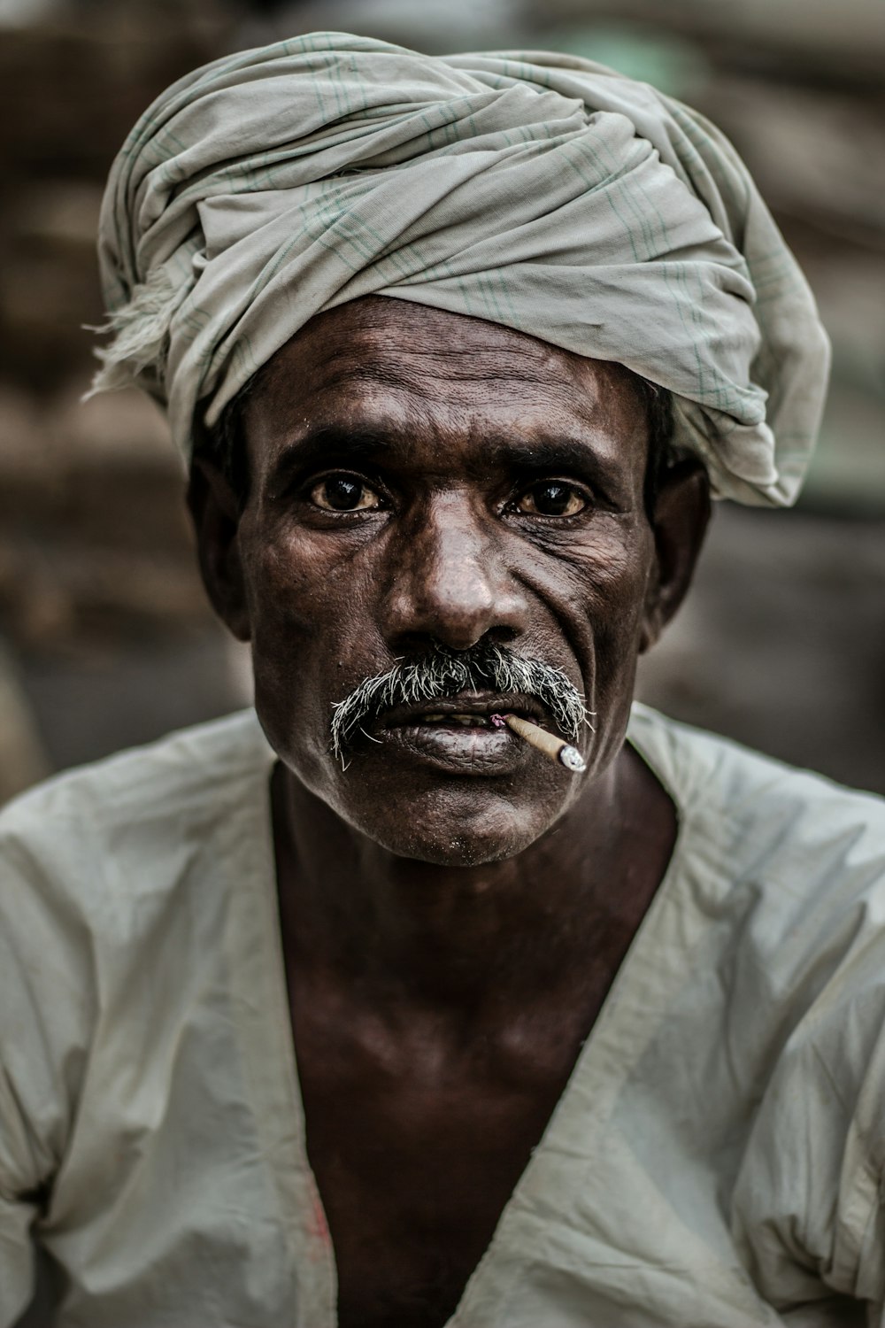 uomo che indossa turbante grigio che fuma sigaretta in fotografia ravvicinata