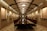 A long, elegant conference room with a reflective wooden table surrounded by chairs. The room is ornately designed with intricate wall panels and curved ceiling beams, lit by pendant lights. The symmetrical layout gives an organized and formal appearance.