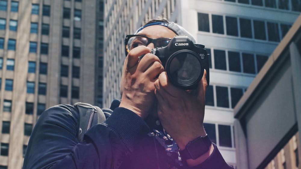 hombre sosteniendo una cámara Canon DSLR