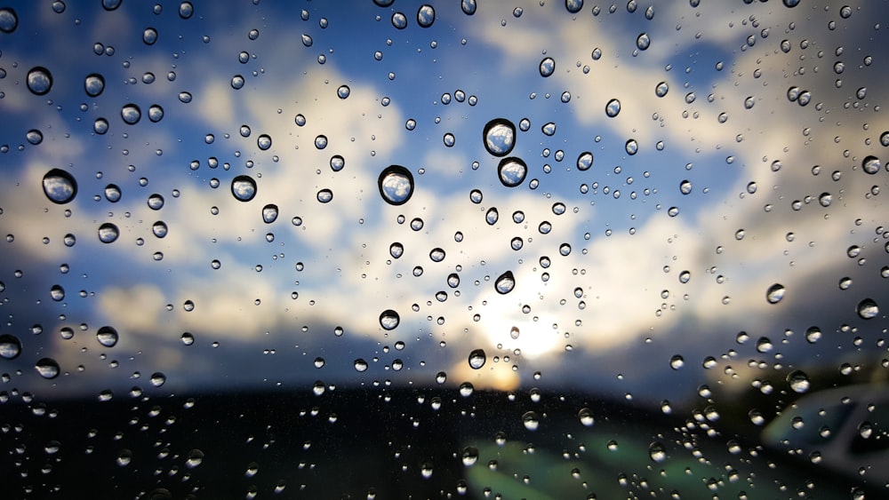 Regentropfen auf ein Fenster mit blauem Himmel im Hintergrund