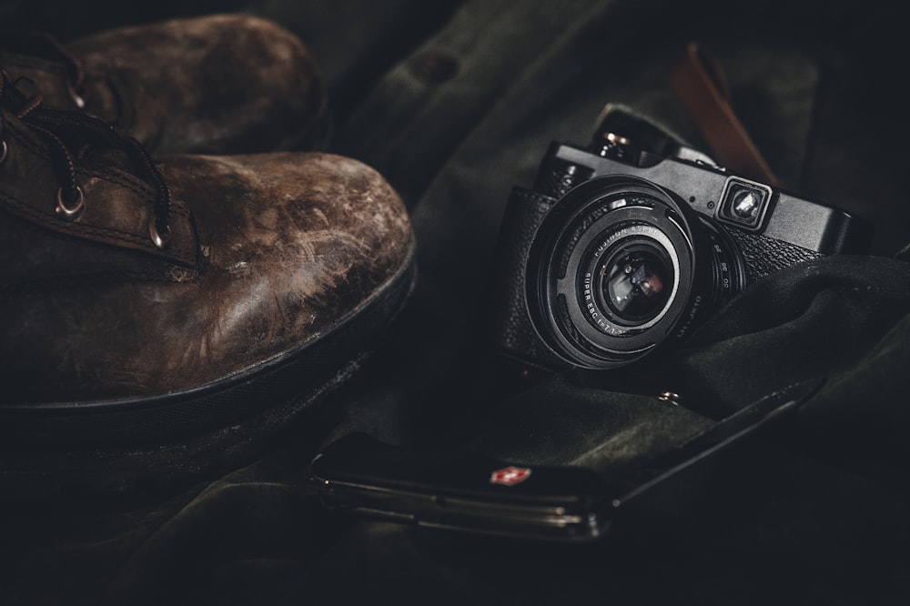 photo of a black point-and-shoot camera and pair of brown leather boots