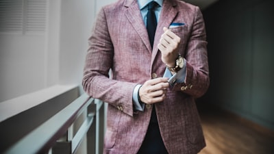 man in maroon suit jacket beside window with railings style teams background