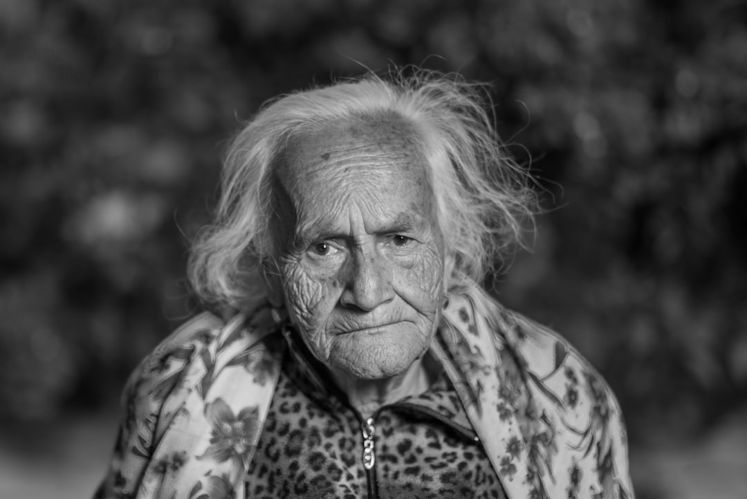 A black and white photo of an older Asian woman looking at the camera.