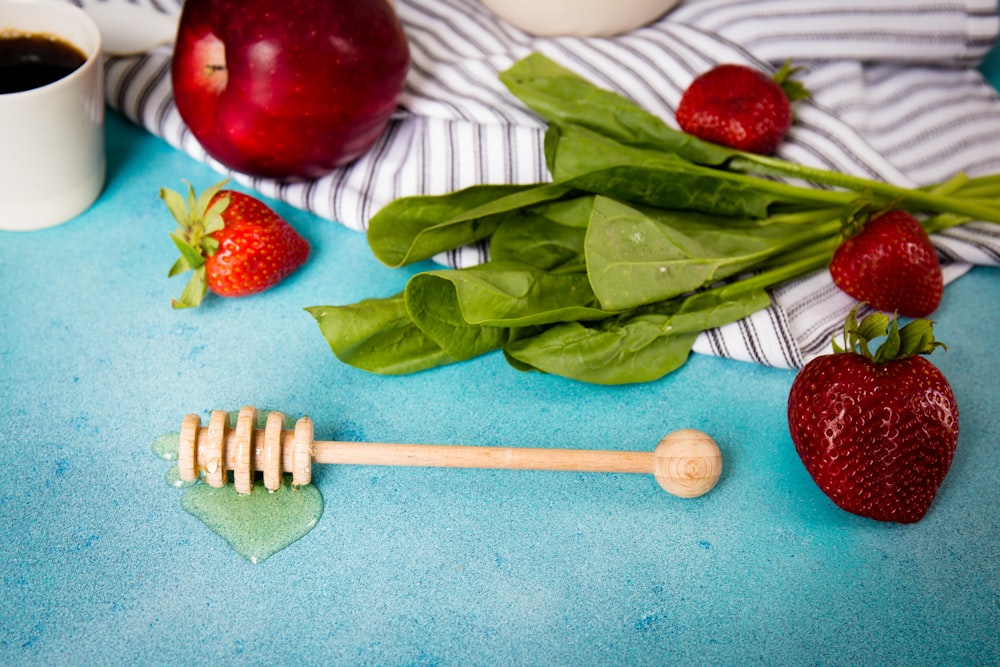 brown honey dipper beside strawberries and apple