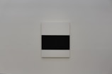 Calm, neutral-toned abstract artwork hanging alone on an off-white wall.