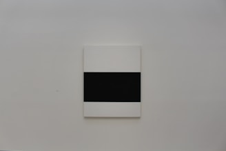 Minimalist modern art canvas hanging on a bright white wall with natural light.