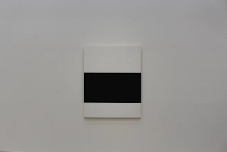 Close-up of a minimalist geometric canvas print with sharp lines and muted tones hanging on a white wall.