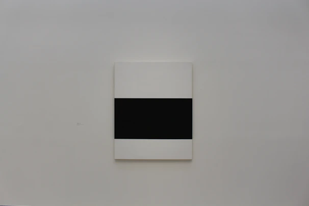 Black and white abstract art piece hanging on a plain white wall