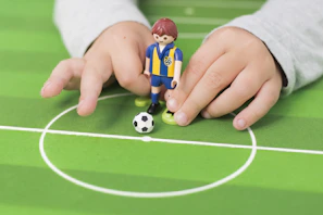 Close-up of a woman’s hand holding a small soccer-themed plush toy with bright stitching