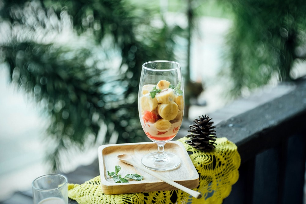 clear footed glass filled with fruits on brown wooden tray