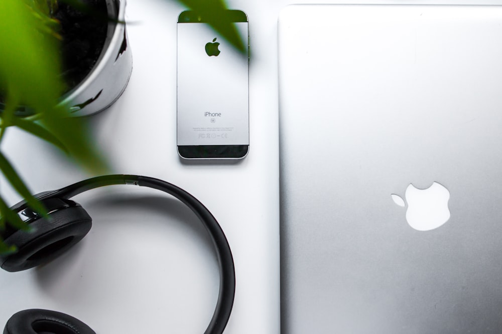 space gray iPhone SE beside headphones and silver MacBook