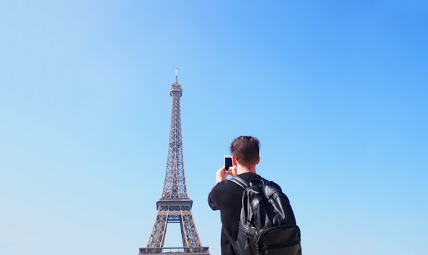 A solo traveler smiling with a backpack in front of a famous city landmark.