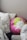 A collection of pillows arranged on a bed or couch. One pillow is round with a vibrant floral design in pink, green, and white colors. Other pillows feature black and white leaf patterns, while another has black and white stripes. The setting appears cozy and inviting.